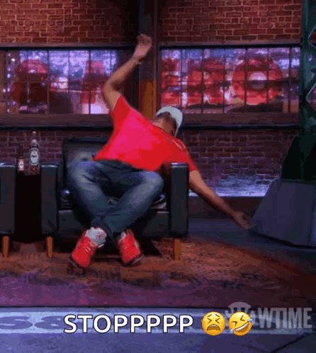 A Man In A Red Shirt Is Sitting In A Chair With His Arms Outstretched And The Words Stoppppp Behind Him GIF