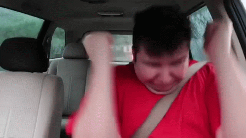 A Man In A Red Shirt Is Sitting In The Back Seat Of A Car GIF