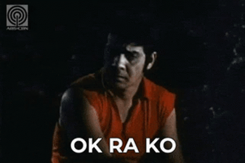 A Man In A Red Shirt Is Sitting In The Dark With The Words Ok Ra Ko Above Him GIF