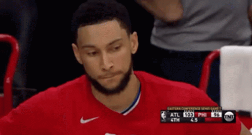 A Man In A Red Shirt Is Sitting In The Stands Watching A Game GIF