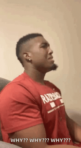 A Man In A Red Shirt Is Sitting On A Couch And Asking Why Why Why Why ? GIF