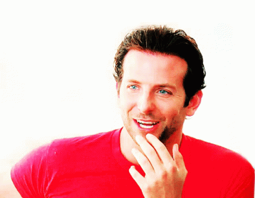 A Man In A Red Shirt Is Smiling And Covering His Mouth GIF