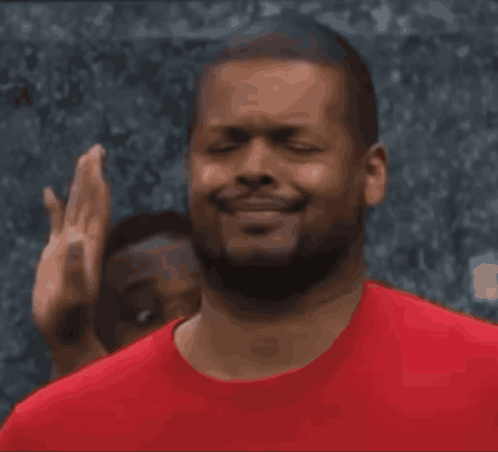 A Man In A Red Shirt Is Smiling And Making A Face GIF