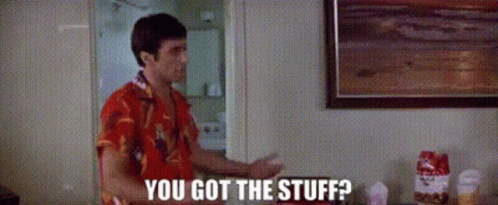 A Man In A Red Shirt Is Standing In A Room Talking To Another Man . GIF