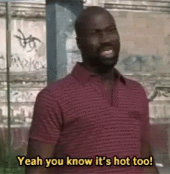 A Man In A Red Shirt Is Standing In Front Of A Building And Saying `` Yeah You Know It 'S Hot Too '' . GIF