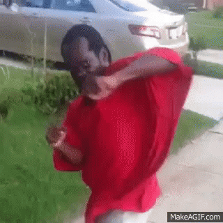 A Man In A Red Shirt Is Standing In Front Of A Car GIF