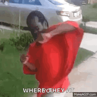 A Man In A Red Shirt Is Standing In Front Of A Car And Says Where They At . GIF