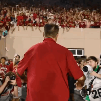 A Man In A Red Shirt Is Standing In Front Of A Crowd With The Number 28 On His Jersey GIF