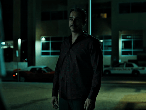 A Man In A Red Shirt Is Standing In Front Of A Police Car And Says Respect You Know GIF