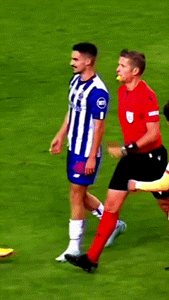 A Man In A Red Shirt Is Standing On A Soccer Field With Players GIF