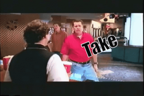 A Man In A Red Shirt Is Talking To A Man In A Black Vest With The Word Take Written On It GIF