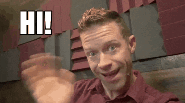 A Man In A Red Shirt Is Waving His Hand In Front Of A Wall That Says Hi . GIF