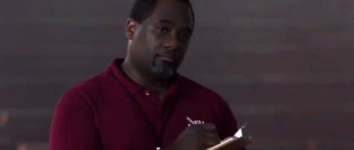 A Man In A Red Shirt Is Writing In A Notebook . GIF