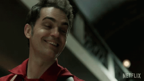 A Man In A Red Shirt Smiles In Front Of A Netflix Logo GIF