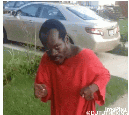A Man In A Red Shirt Stands In Front Of A Car GIF