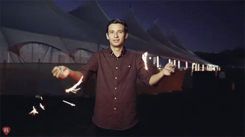 A Man In A Red Shirt Stands In Front Of A Tent With A Fl Logo On The Bottom GIF