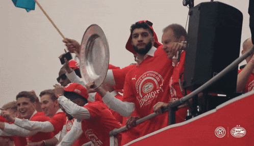 a man in a red shirt that says ' psv ' on it is holding a trophy