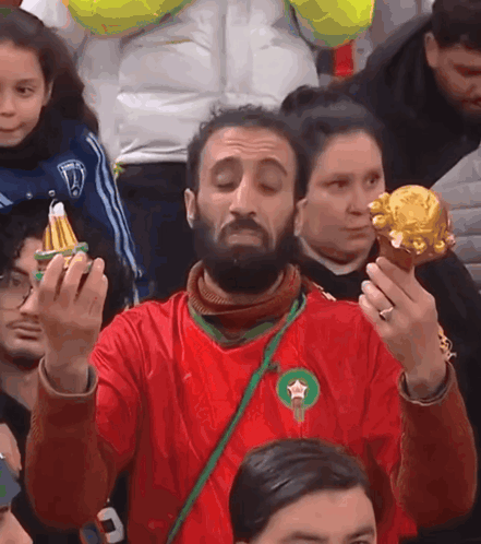 a man in a red shirt with a green star on it holds a gold object