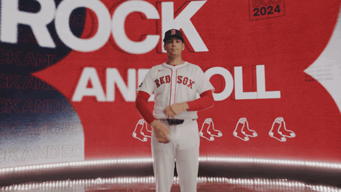 A Man In A Red Sox Jersey Stands In Front Of A Boston 2024 Poster GIF