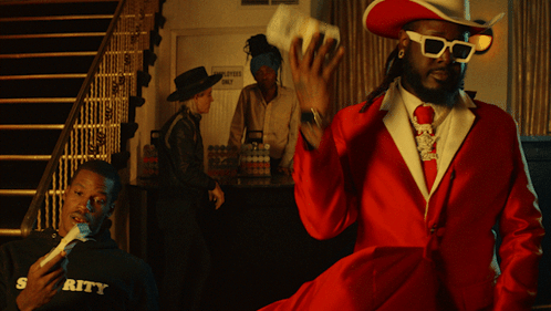 A Man In A Red Suit And Cowboy Hat Stands In Front Of A Sign That Says Employment Only GIF