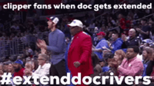 A Man In A Red Suit Is Dancing In A Crowd Of People At A Basketball Game . GIF