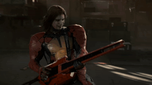 A Man In A Red Suit Is Holding A Guitar GIF