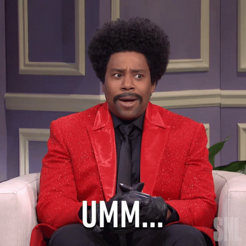 A Man In A Red Suit Says Umm While Sitting On A Chair GIF