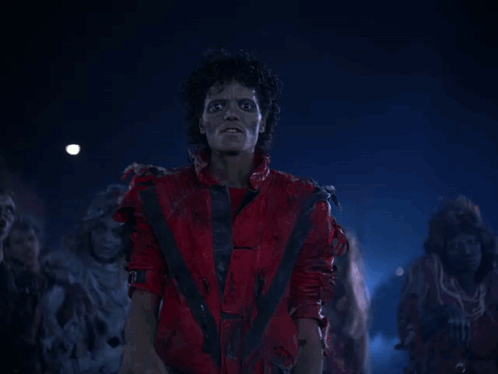 A Man In A Red Suit Stands In Front Of A Group Of Zombies GIF