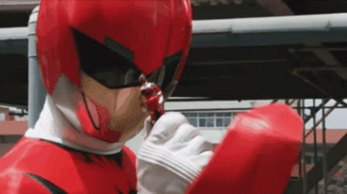 A Man In A Red Superhero Costume Is Holding Something In His Hand GIF