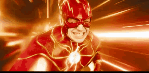 A Man In A Red Superhero Costume Is Smiling With A Flash Coming Out Of His Mouth . GIF