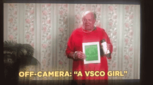 A Man In A Red Sweater Is Holding A Cup And A Piece Of Paper In Front Of A Camera . GIF