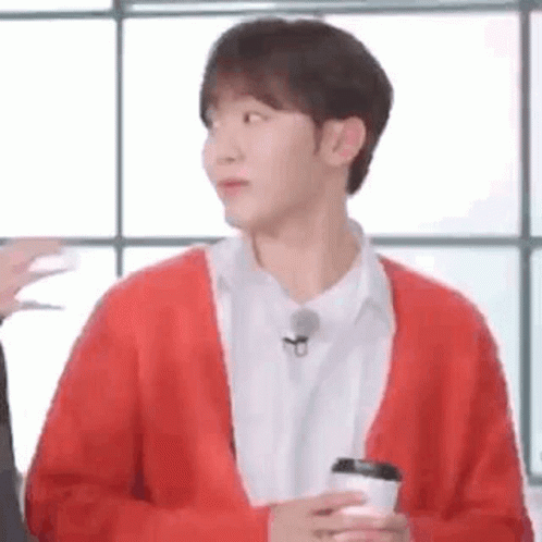 A Man In A Red Sweater Is Holding A Cup Of Coffee . GIF