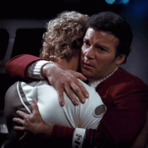 A Man In A Red Sweater Is Hugging Another Man In A White Shirt GIF