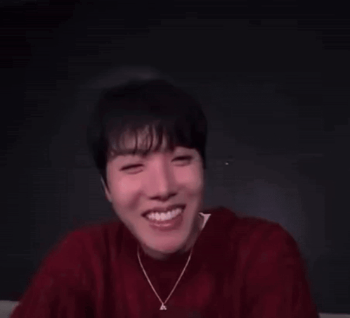 a man in a red sweater is making a funny face with his eyes closed .