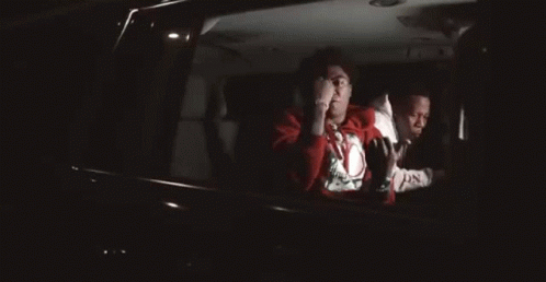 a man in a red sweater is sitting in the back seat of a car .