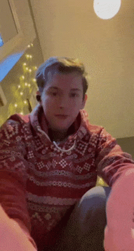 A Man In A Red Sweater Is Sitting On A Couch GIF
