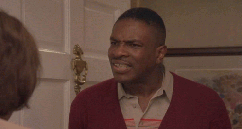 A Man In A Red Sweater Stands In Front Of A Door GIF