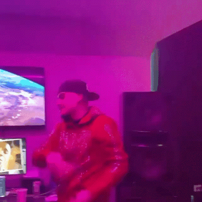 A Man In A Red Sweatshirt Is Dancing In Front Of A Purple Light GIF