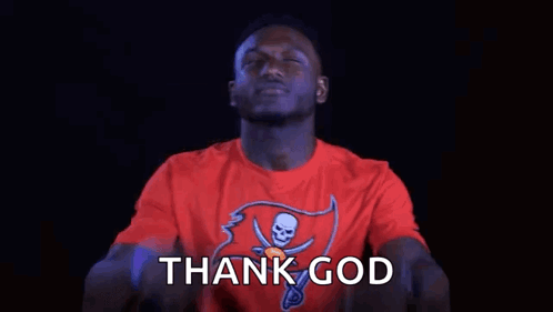 a man in a red t-shirt is pointing up with his fingers and saying thank god .