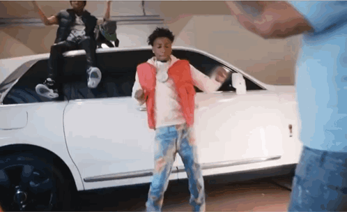 A Man In A Red Vest Is Dancing In Front Of A White Limousine GIF
