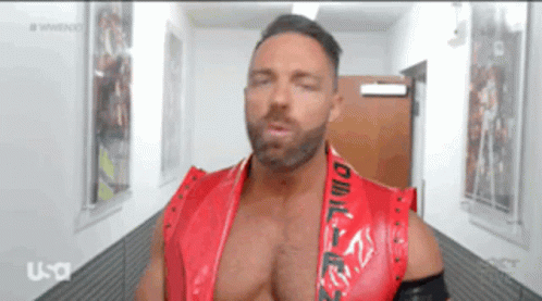 A Man In A Red Vest Is Standing In A Hallway GIF