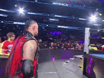 A Man In A Red Vest Stands In Front Of A Crowd At A Smack Wrestling Event GIF
