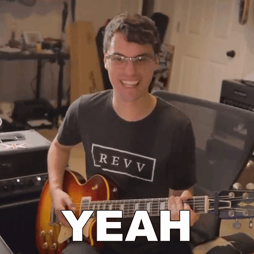 A Man In A Revv Shirt Is Playing A Guitar And Says Yeah GIF