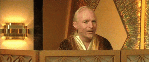 A Man In A Robe Is Sitting In Front Of A Window . GIF