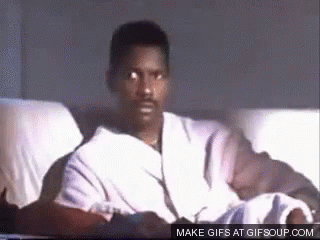 A Man In A Robe Is Sitting On A Couch And Looking At The Camera . GIF