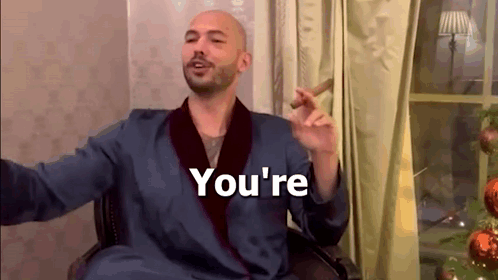 A Man In A Robe Is Smoking A Cigar And Saying `` You 'Re '' While Sitting In A Chair . GIF