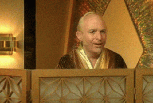 A Man In A Robe Stands Behind A Wooden Partition GIF