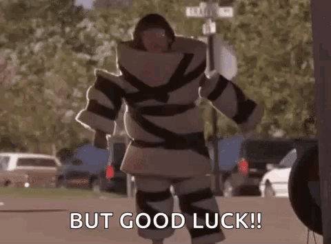 A Man In A Robot Costume Is Walking Down The Street And Saying `` But Good Luck '' . GIF