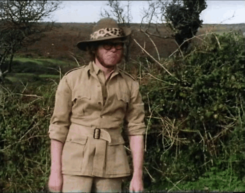 A Man In A Safari Outfit With A Leopard Print Hat And Glasses GIF