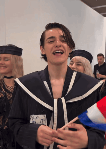 A Man In A Sailor Costume Is Smiling And Holding A French Flag GIF